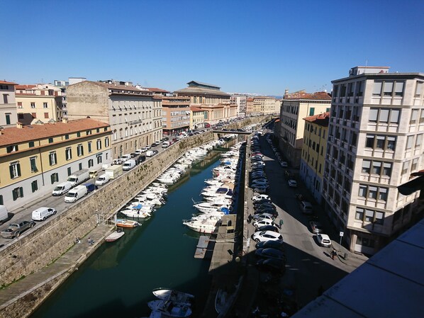 Un port de plaisance où des bateaux sont amarrés le long d’un canal, entouré d’immeubles à plusieurs étages dotés de balcons.