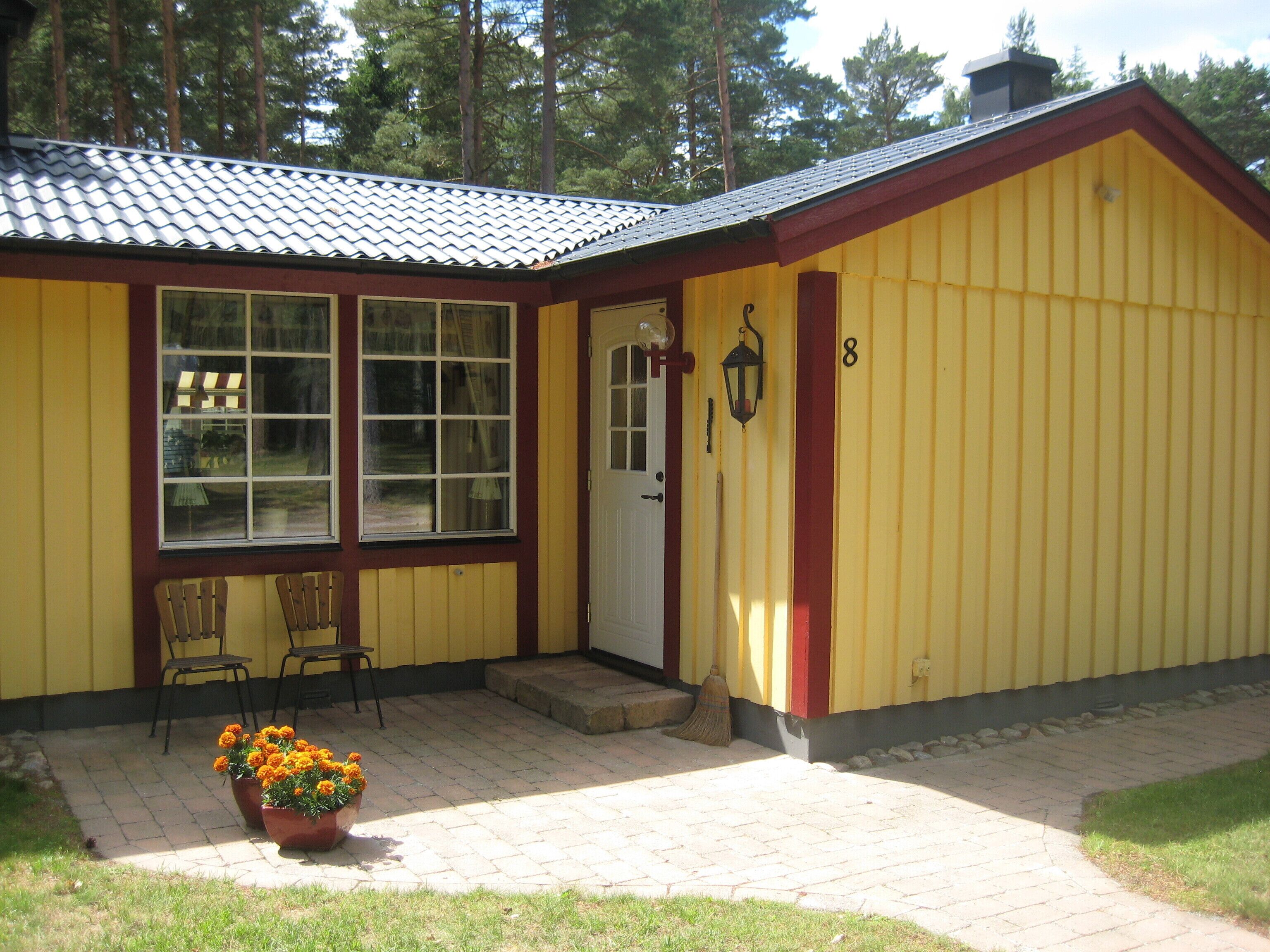 A yellow building with a red door, numbered 8, and two windows.
