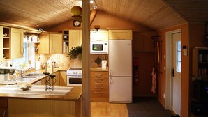 A compact kitchen with wooden cabinets, a microwave, a refrigerator, and a sink. - Lovely cottage in Juleboda, close to the sea with wonderful sandy beach (Degeberga)