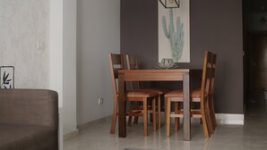 A dining area with a wooden table and chairs, a cactus artwork on the wall, and a modern light fixture above the table. - Exposito's Vacation Home  (Las Palmas de Gran Canaria)