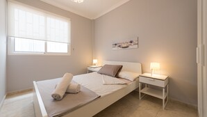 A bedroom with a bed, bedside tables, a window, and a painting on the wall. - Exposito's Vacation Home  (Las Palmas de Gran Canaria)