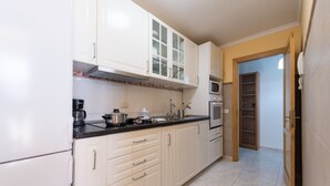 A kitchen with white cabinets, a microwave, and a stove. There is a door leading to a pantry. - Exposito's Vacation Home  (Las Palmas de Gran Canaria)