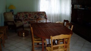 A dining area with a wooden table and chairs, a floral sofa, and a bookshelf. - Recent villa in quiet traditional neighborhood (Andernos-Les-Bains)