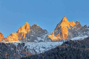 A mountain range with snow-covered peaks and a forested valley. - Basecamp Town Centre 2 Bed Ground Floor Apartment with Terrace (Chamonix-Mont-Blanc)
