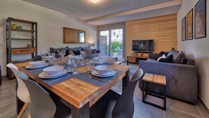 Una sala de estar moderna con comedor, un sofá, un televisor y una pared de madera.