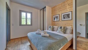 Un dormitorio con cabecera de madera, un ventanal grande y una cama con toallas ordenadas.
