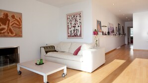 A modern living room with a white sofa, a small table with wheels, and a fireplace. - beautiful (Sitges)