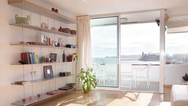 A modern living room with a large sliding glass door leading to a balcony with a city view. - beautiful (Sitges)