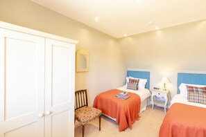 A bedroom with two beds, a chair, a nightstand, and a wardrobe. - Swilken View, 5 Star Selfcatering House Overlooking the Old Course in St Andrews (St Andrews)