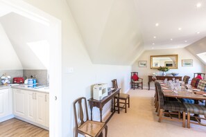 A dining area with a long table set for six, surrounded by plaid upholstered chairs. - Swilken View, 5 Star Selfcatering House Overlooking the Old Course in St Andrews (St Andrews)