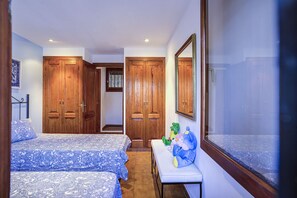 A bedroom with two beds, wooden wardrobes, a small table with toys, and a large mirror. - Villa by the sea with private pool and wifi (Las Casas de Alcanar)