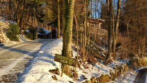 Un sentiero innevato che conduce a una baita rustica, con un cartello che indica 'LISTER-OT RAIN 14'.
