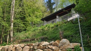 Un rustico chalet con parete in pietra e balcone, immerso nel verde.