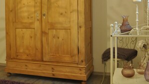 Un'armadio in legno con due ante, un tavolino con un vaso e un tappeto viola.