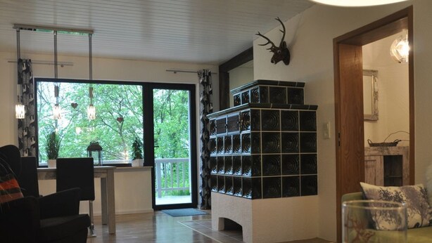 Un soggiorno moderno con pavimento in legno, un divano nero, un tavolino da caffè in vetro e una libreria.