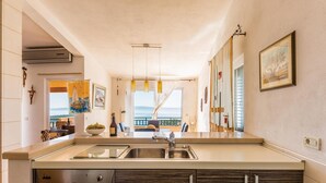 Una cocina con un amplio ventanal, horno empotrado y un lavamanos.