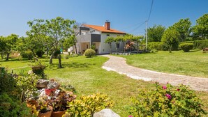 Una casa moderna de dos pisos con un camino pavimentado que conduce a la entrada.