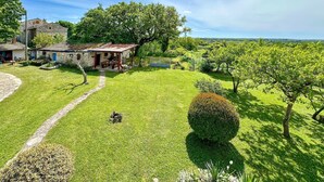 Una casa de piedra con jardín, un sendero empedrado y vistas al campo.