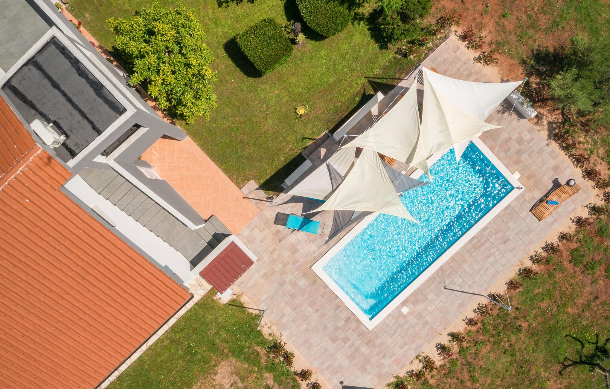 An aerial view of a property with a swimming pool, outdoor seating, and a well-maintained garden.