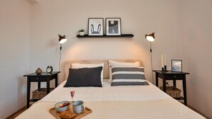 A neatly made bed with pillows, a bedside table with a clock, and a tray with food and a drink. There are two wall-mounted lamps and framed pictures above the bed. - 3 bedroom beautiful apartment in Makarska (Makarska)