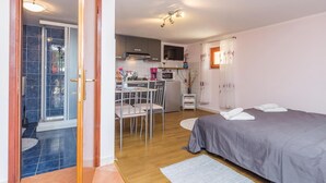 Espaço compacto com cozinha compacta, área de refeições e quarto com cama e toalhas.