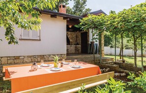 Ein Essbereich im Freien mit einem Tisch für vier Personen, einer Steinmauer und einem überdachten Patio-Eingang.