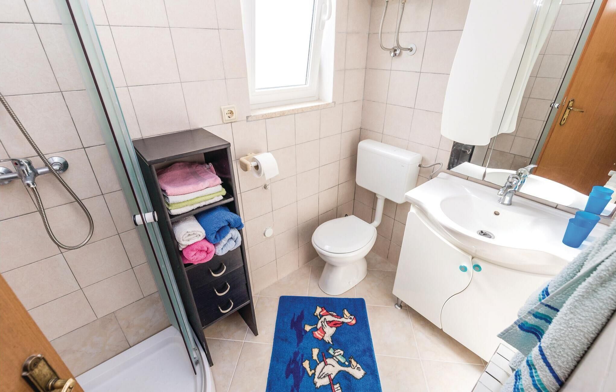 Une salle de bain équipée de toilettes, d’un lavabo, d’une douche et d’un porte-serviettes avec des serviettes pliées.