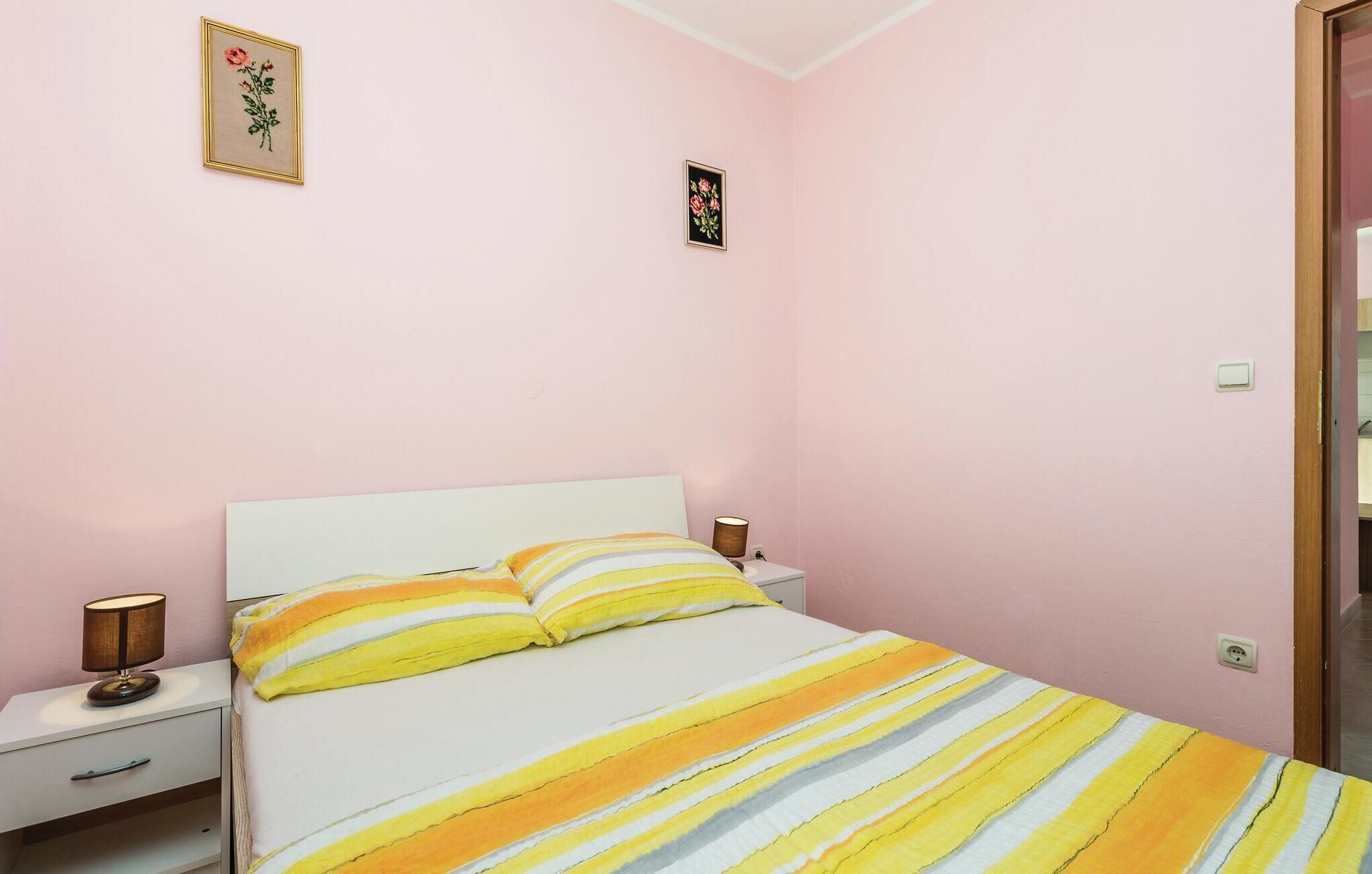 A bedroom with a bed, two bedside tables, and two lamps.