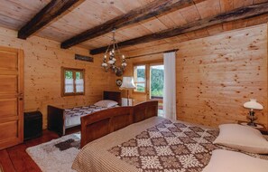 Camera da letto in una baita di legno con due letti, un lampadario e una finestra con tende.