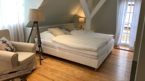 A modern bedroom with a large bed, a chair, a lamp, and a view of the outside.