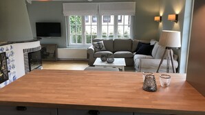 A modern living room with a wooden island, a sofa, a coffee table, and a TV.
