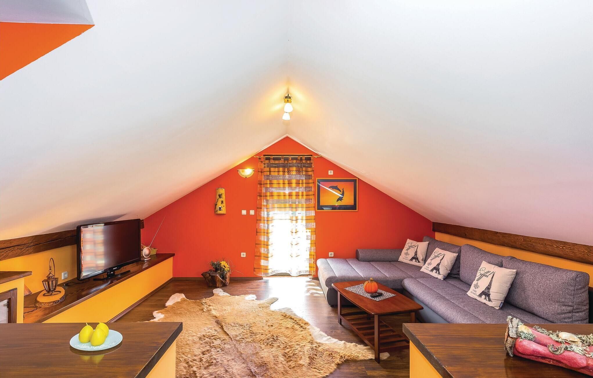 A cozy attic room with a sloped ceiling, a sofa with Eiffel Tower pillows, a wooden coffee table, and a TV on a wooden stand.