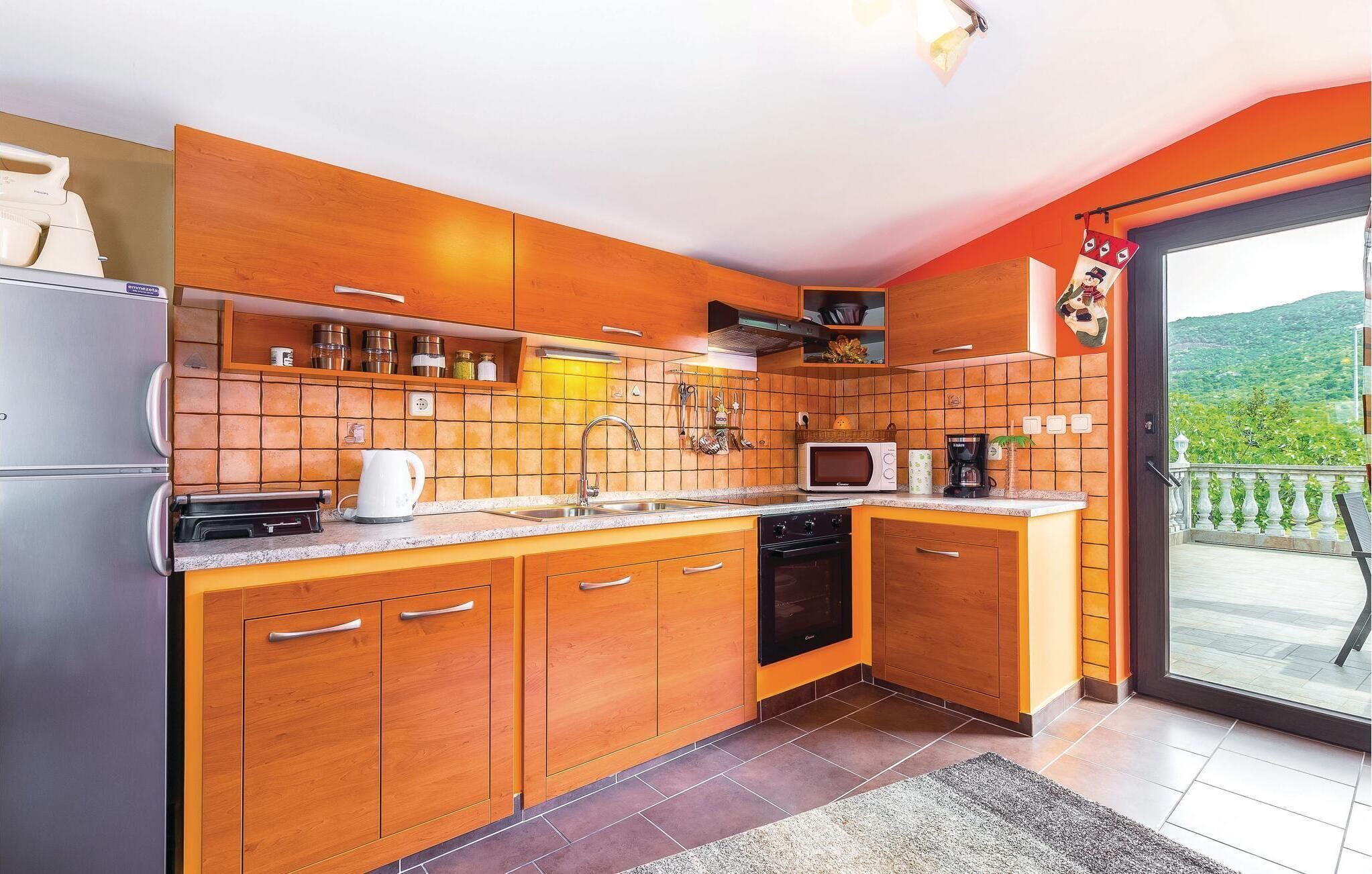Une cuisine moderne avec des meubles en bois, un réfrigérateur en acier inoxydable, un four à micro-ondes et une machine à café.