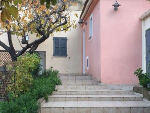 Un conjunto de escalones de piedra que conducen a un edificio rosa con una ventana y una puerta.