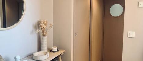 A hallway with a wooden console table, a mirror, a vase with dried flowers, and a door.