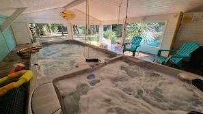 A hot tub with a wooden deck, a clock, and outdoor chairs. - Gite with its private INDOOR swimming pool 30°  JACUZZI 36° private land 3000 m² (Naujac-Sur-Mer)