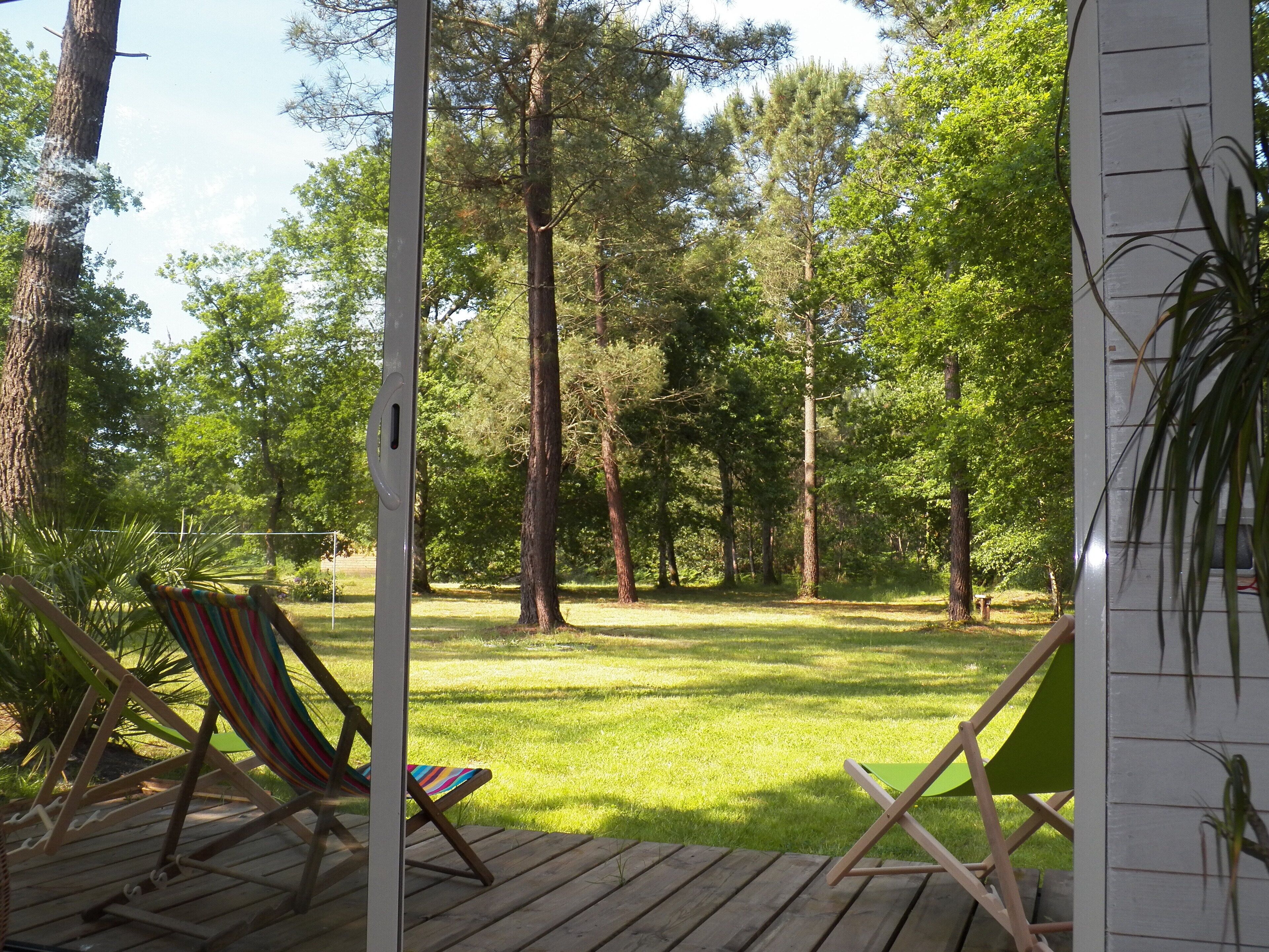 A wooden deck with two striped chairs and a green folding chair.