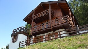 Een houten chalet met meerdere balkons, een witte gevel en een houten omheining eromheen.
