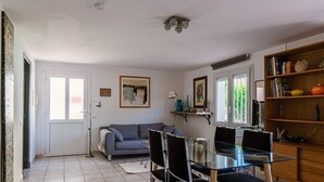 Un comedor con mesa y sillas de vidrio, un sofá gris y una estantería de madera.