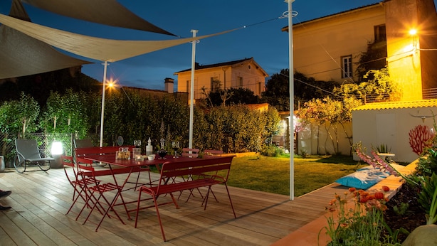 Un patio al aire libre con cubierta de madera, una mesa metálica roja y sillas.