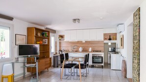 Una cocina moderna con comedor, un televisor sobre una mesa de vidrio y una estantería de madera.