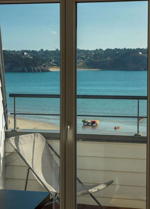 A balcony with a view of the beach, a chair, and a table. - Quiet top floor flat with sea view (Crozon)