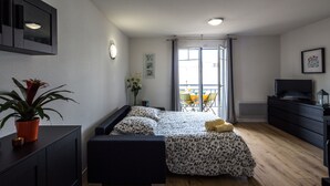 Une chambre à coucher moderne avec un lit, un bureau, une commode et une plante en pot.