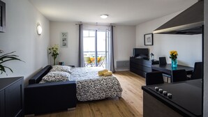 Une chambre moderne et bien éclairée, équipée d’un lit, d’un bureau et d’un coin repas.