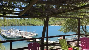 A covered outdoor seating area with a view of a marina and boats. - 'MARJOLAINE' Gite T2 / VIEW OF THE LAKE 200 m away from the beaches (BAUDUEN)