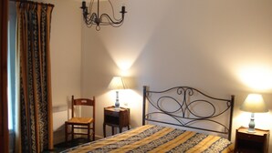 A bedroom with a bed, two bedside tables with lamps, a chair, a chandelier, and patterned curtains. - EDONIAA vacation rentals in the heart of the Bay of Somme (Quend)