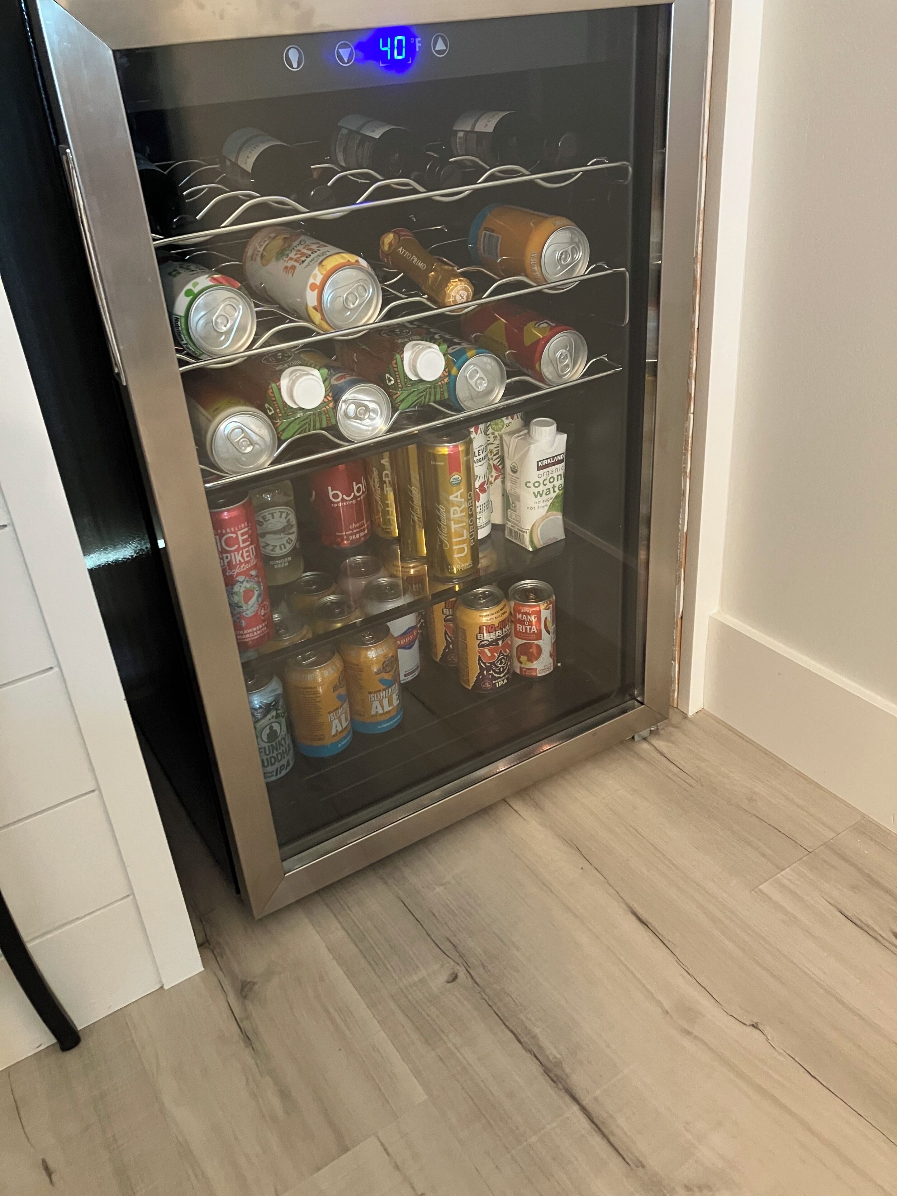 A beverage refrigerator stocked with various drinks including cans and bottles.