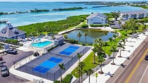 Ein Resort mit Schwimmbad, Tennisplätzen und Meerblick.