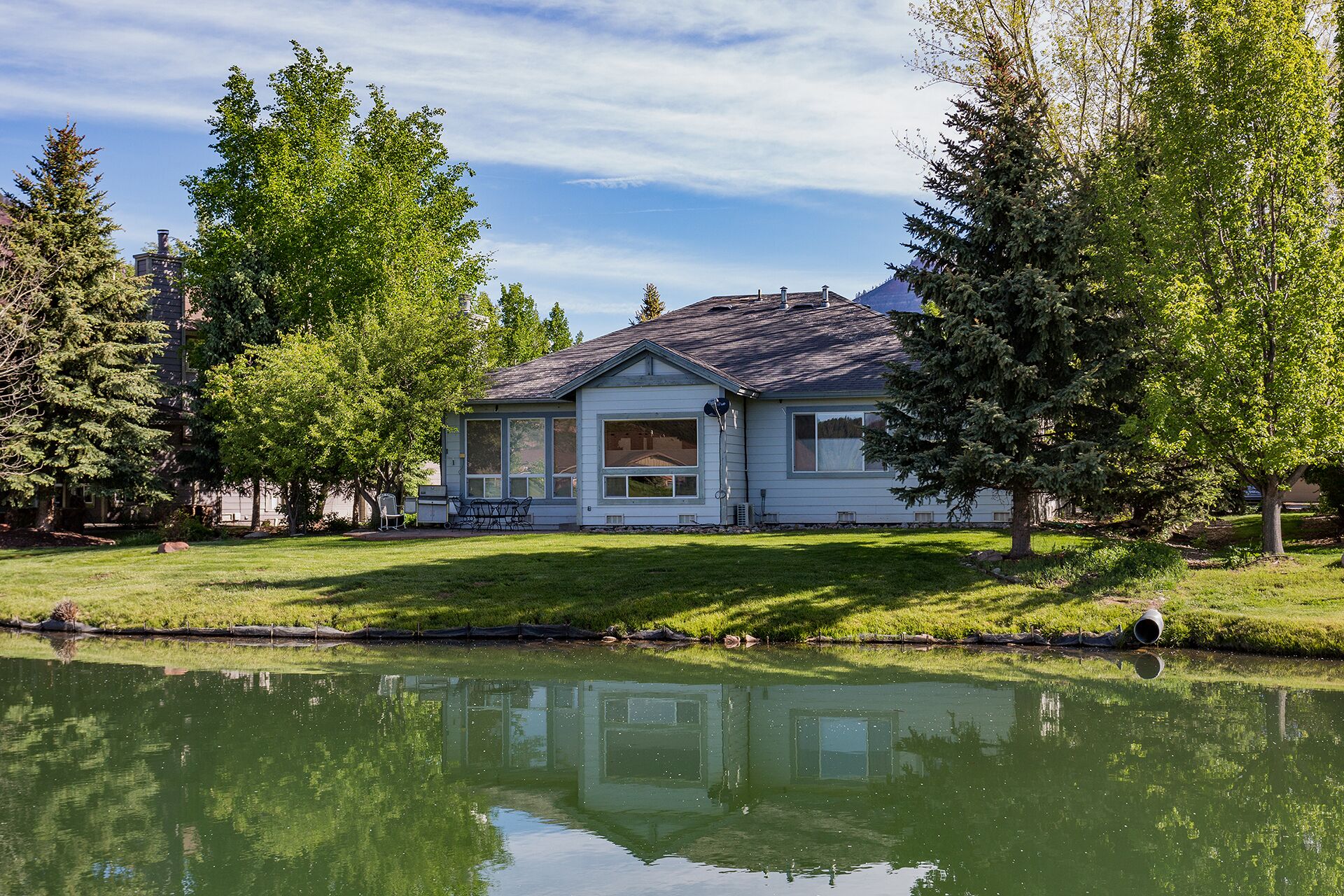 A house with a large window, a porch, and a pond in front.