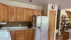 A kitchen with wooden cabinets, a white refrigerator, and a clock on the wall.